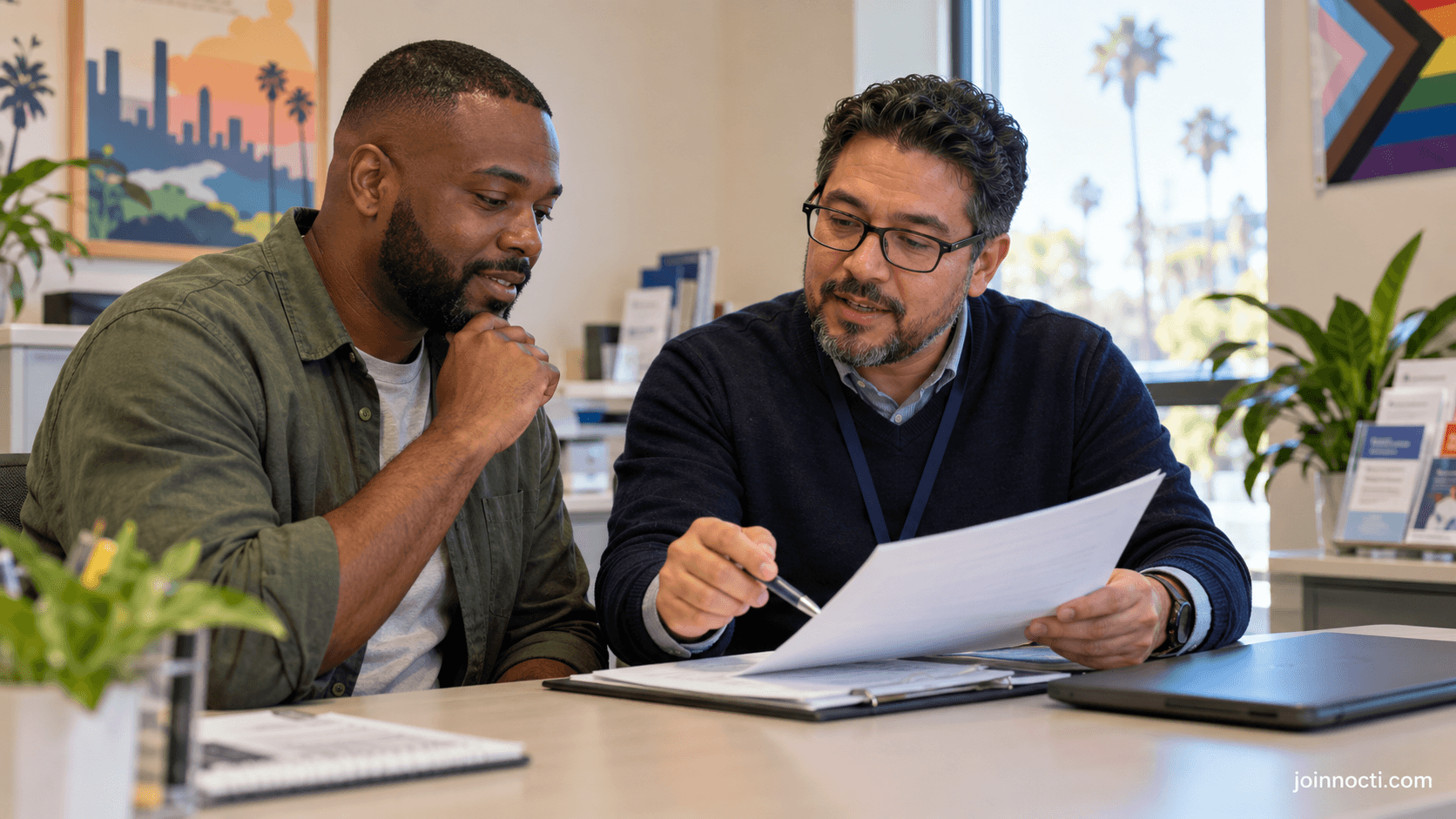 Adult man reviewing California health-benefit paperwork with a supportive enrollment counselor in a private community office
