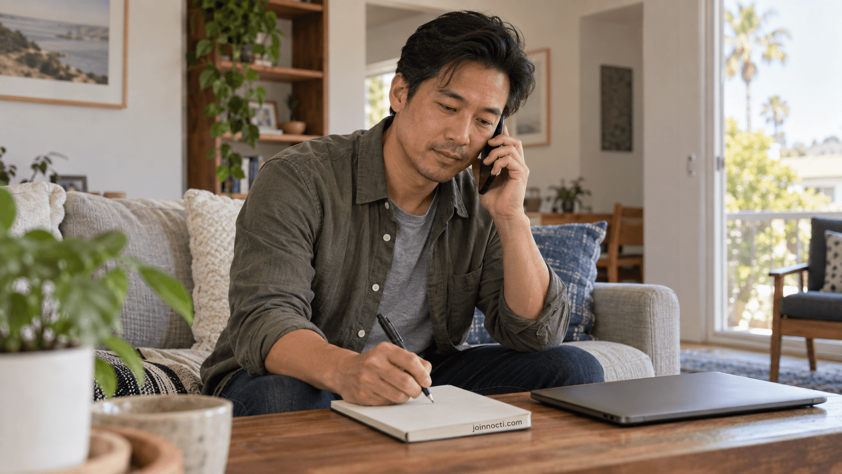 Man making a private support call while writing notes at home in Southern California