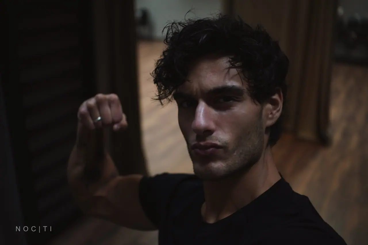 Adult male model in a dark room illustrating a quiet post-Halloween recovery routine