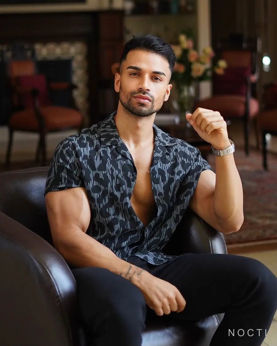 Seated adult male editorial model beneath a subtle NOCTI mark for a Los Angeles massage booking checklist