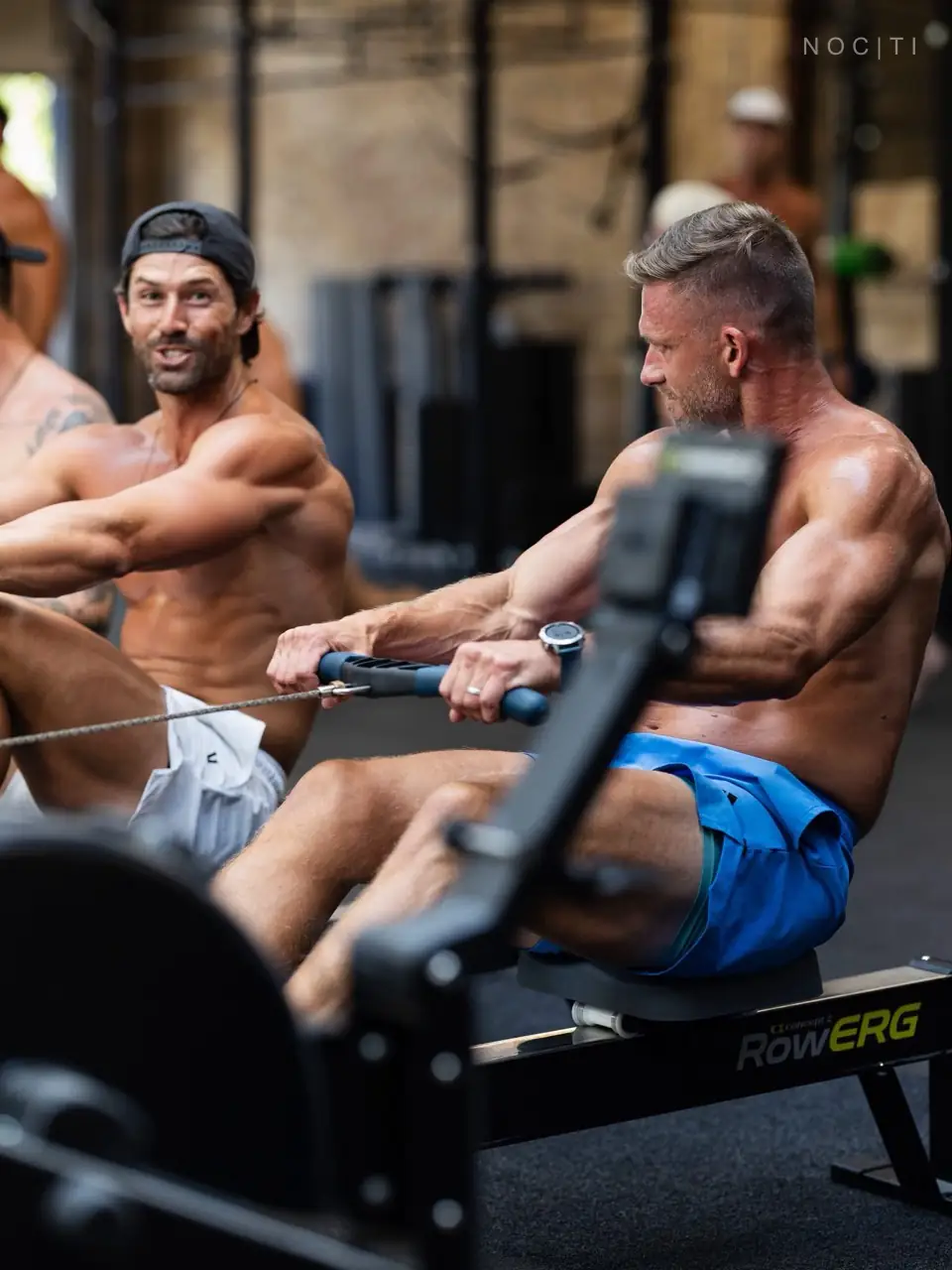 Adult men exercising on rowing machines in an editorial image about communication and professional massage boundaries