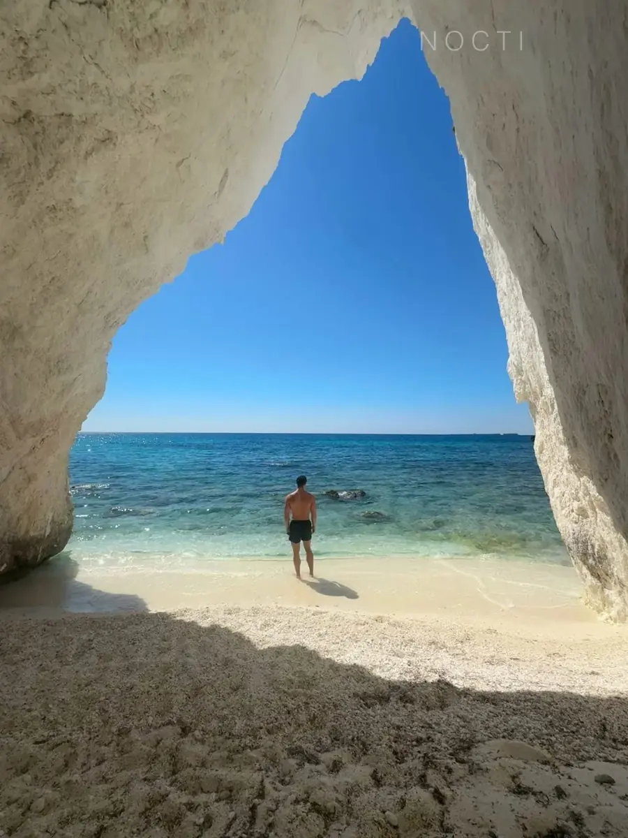 Adult male model standing at the edge of the sea beneath a subtle NOCTI mark, illustrating a career reset